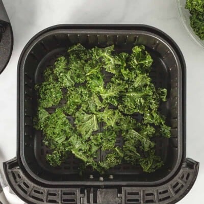 Kale chips in an air fryer basket.