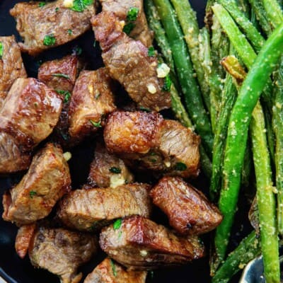 tender steak bites on black plate.